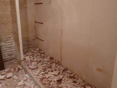Un muro parcialmente demolido con escombros caídos esparcidos en la parte inferior en un espacio interior.